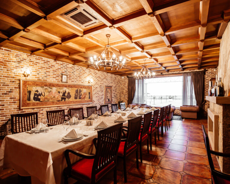restaurant table for 14 persons at restaurant hall with brick walls wide windows and wood ceiling